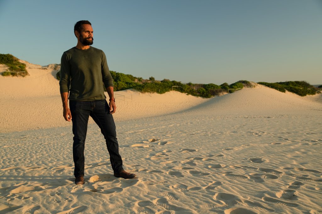 Presenter Rob Collins standing near sand dunes
